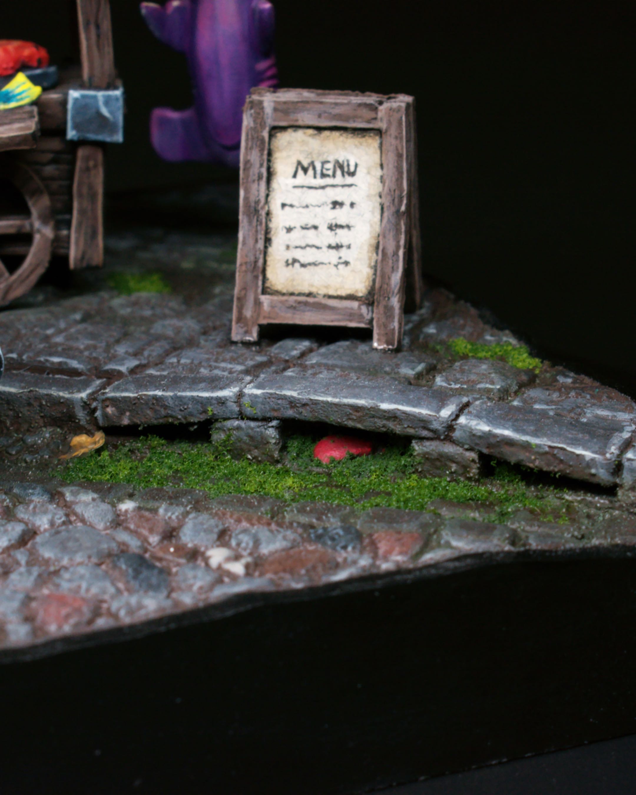 Close view of the miniature menu sign and textured street.